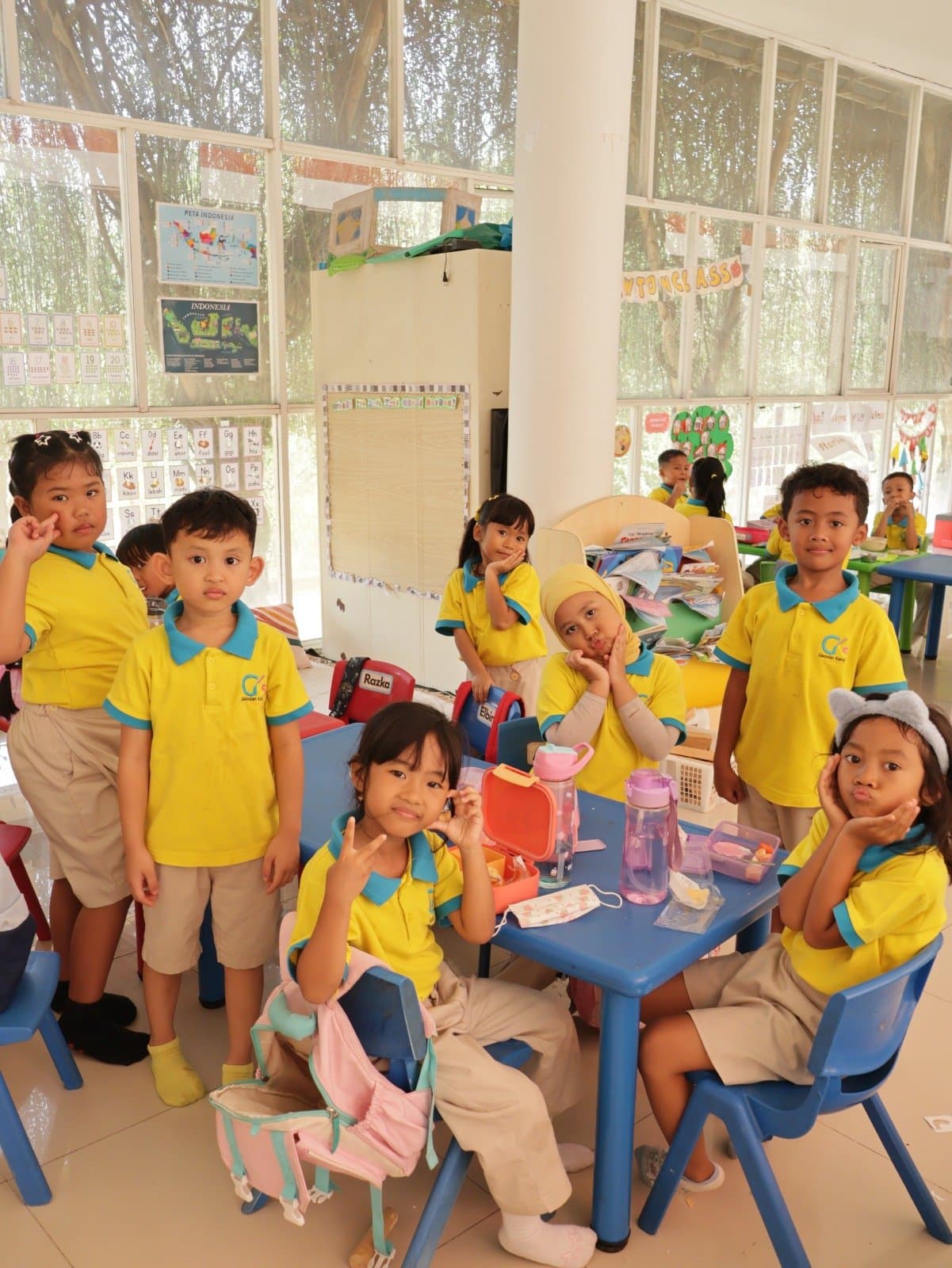 Children sitting on the classroom floor, raising their hands